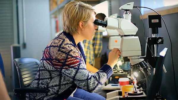 woman looking into microscope